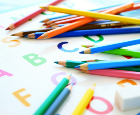 alphabetical letters and colored pencils with parents teaching kids phonics