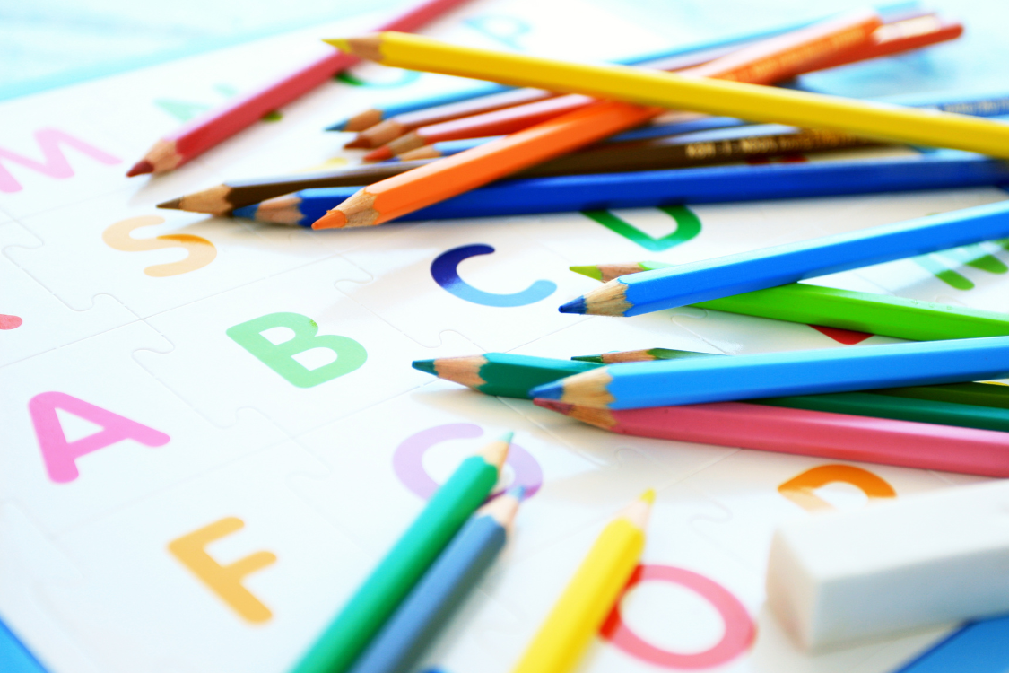 alphabetical letters and colored pencils with parents teaching kids phonics