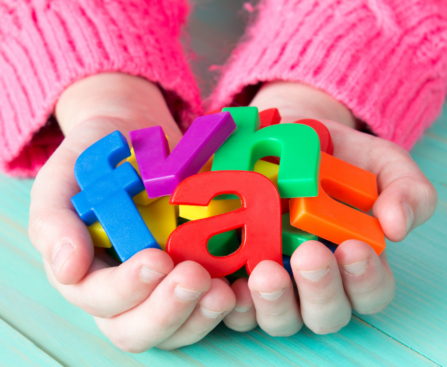 a child holding a collection of colorful plastic ABC letters in their hands