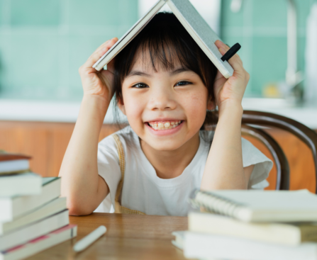 a bright smiling young girl is reading books